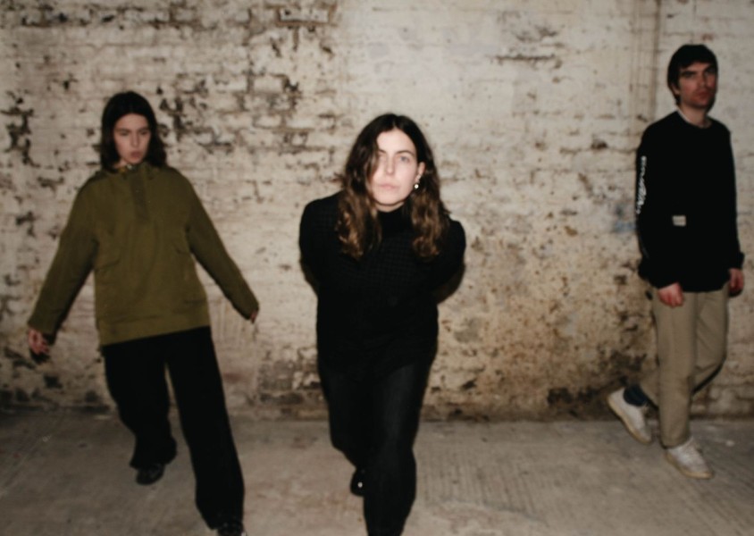 Trio Voka Gentle stood in front of a brick wallx